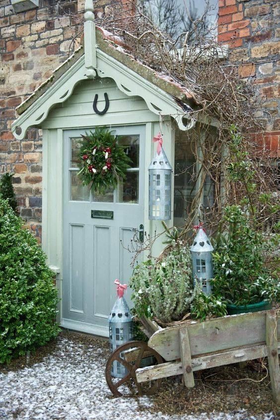 a garden shed with christmas wreaths on the door and decorations in pots around it