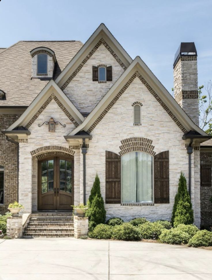 a large brick house with brown shutters on the front door and windows in the middle