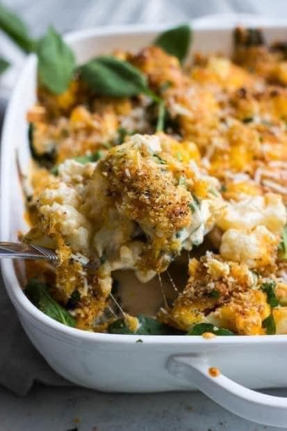 a casserole dish with broccoli, cheese and spinach sprinkled on top