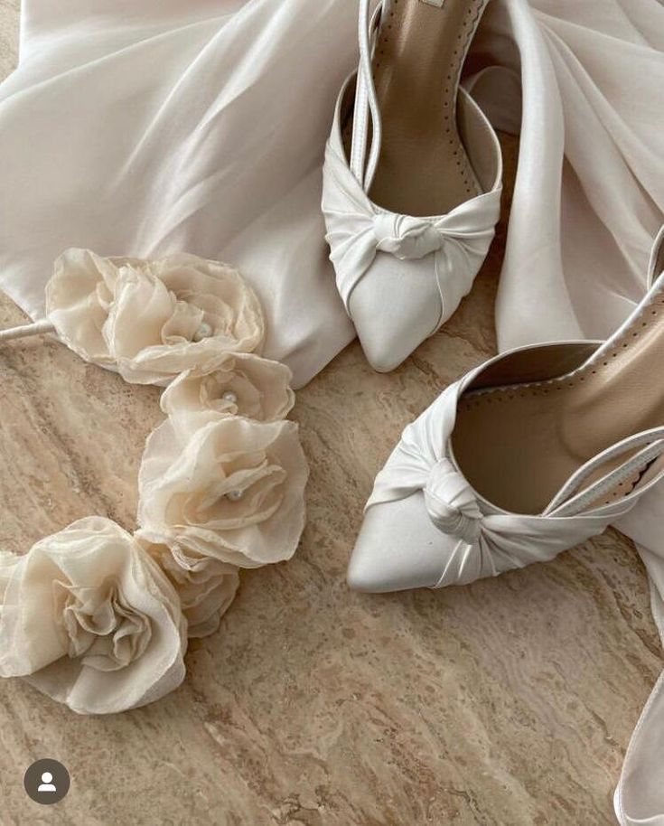 two pairs of white shoes with flowers on the bottom and one pair of high heeled shoes