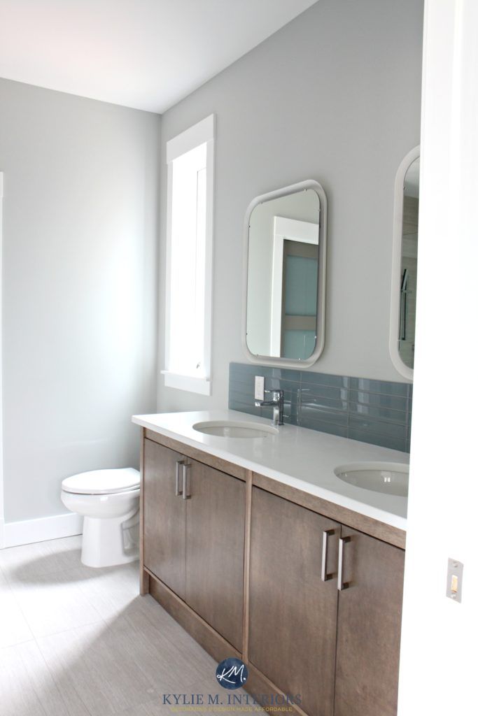 a white toilet sitting next to a sink in a bathroom under two mirrors on the wall