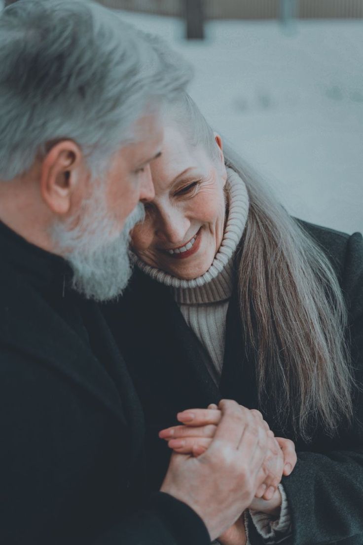 an older couple holding hands and smiling at each other