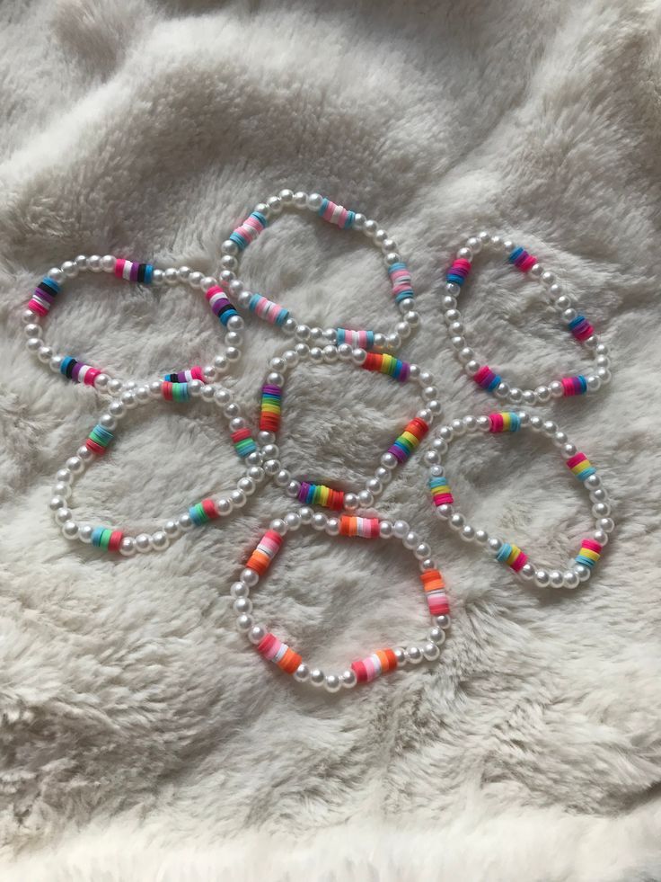 four bracelets with multicolored beads on white fur