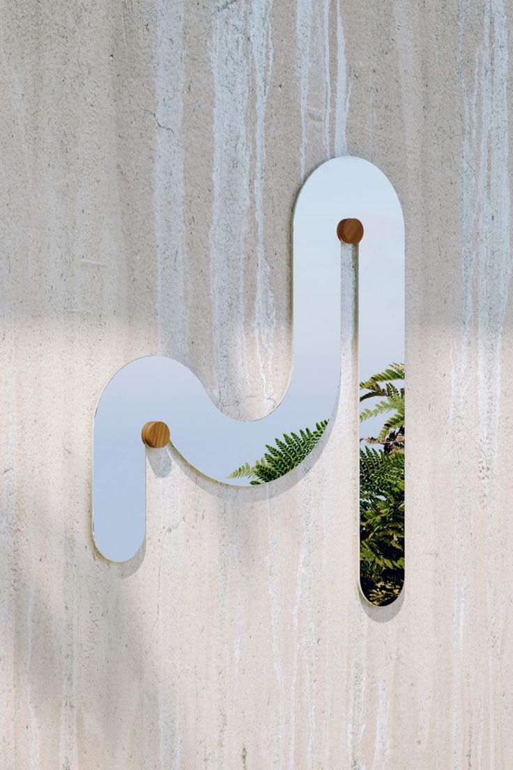 a clock mounted to the side of a wall next to a mirror and palm tree