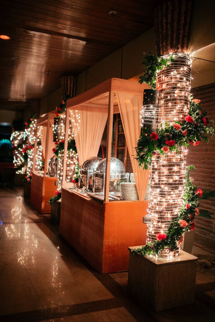 an outdoor buffet with lights and decorations on the walls, along with potted plants