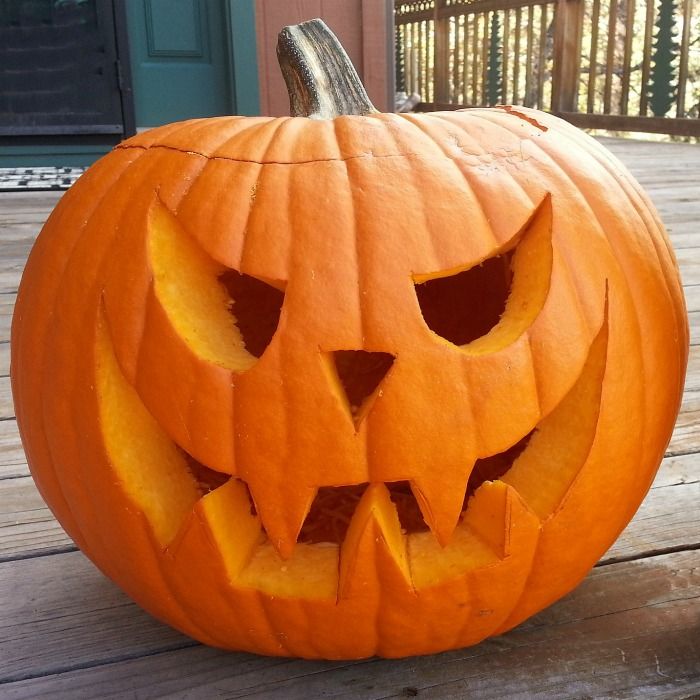 a carved pumpkin sitting on top of a wooden porch