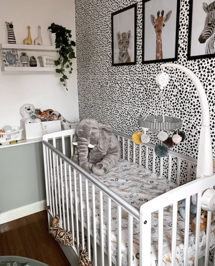 a baby crib with an elephant and giraffe wallpaper in the corner