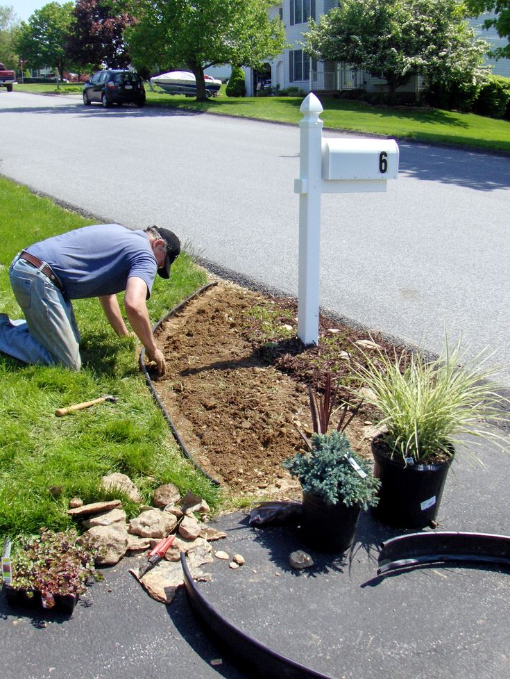 a man digging in the ground next to a mailbox