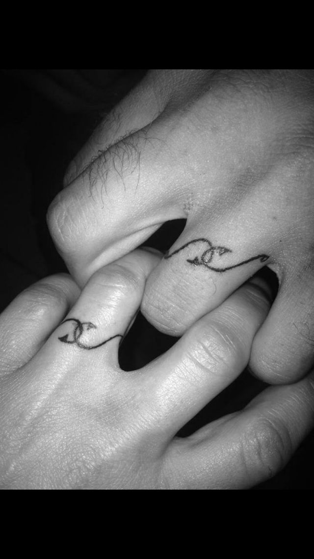 two hands holding each other with tattoos on their fingers and the words love are written in cursive letters