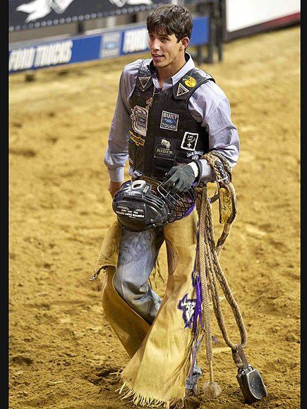 a man in cowboy gear walking across a dirt field