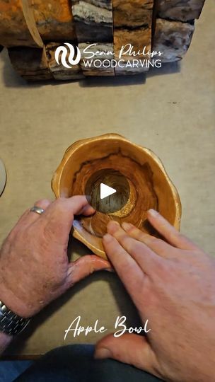 a man is working on an apple bowl with wood carving tools in the back ground