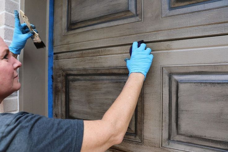 a man in blue gloves is painting the front door