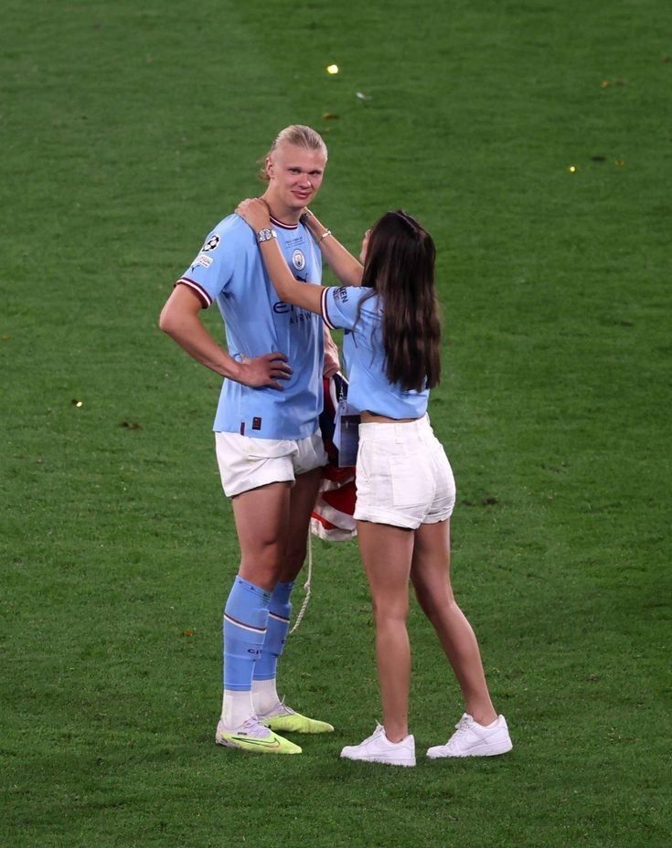 two female soccer players are standing on the field and hugging each other while one is holding her head