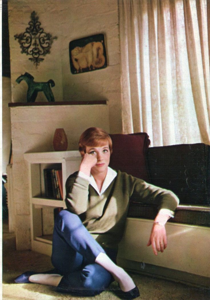 a woman sitting on the floor next to a book shelf