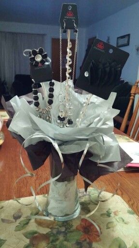 a vase filled with jewelry sitting on top of a table next to a wooden table