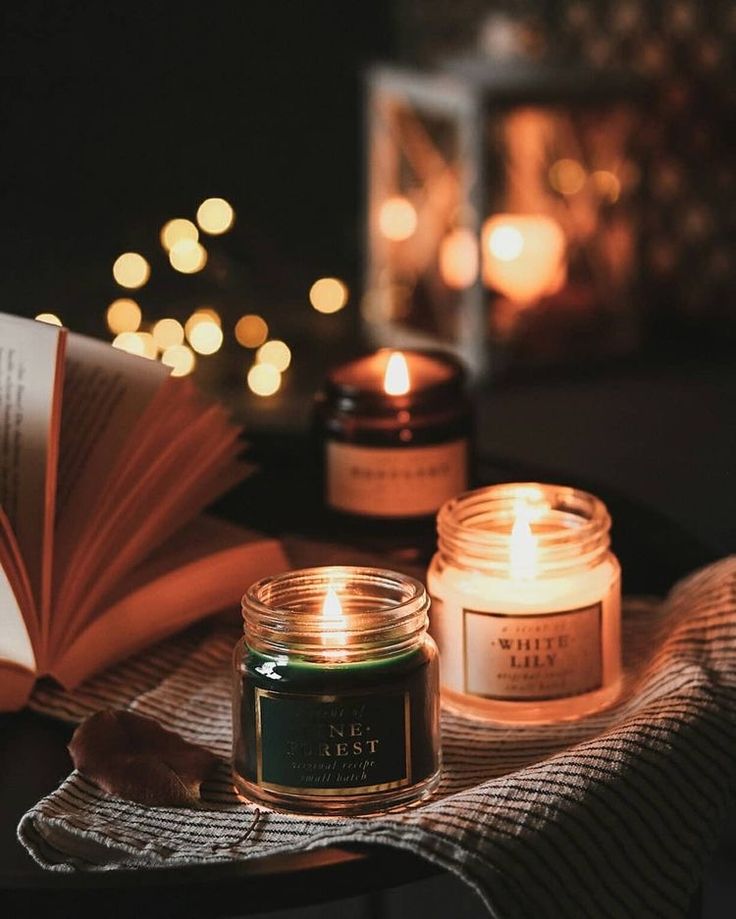 two candles sitting on top of a table next to an open book and a lit candle