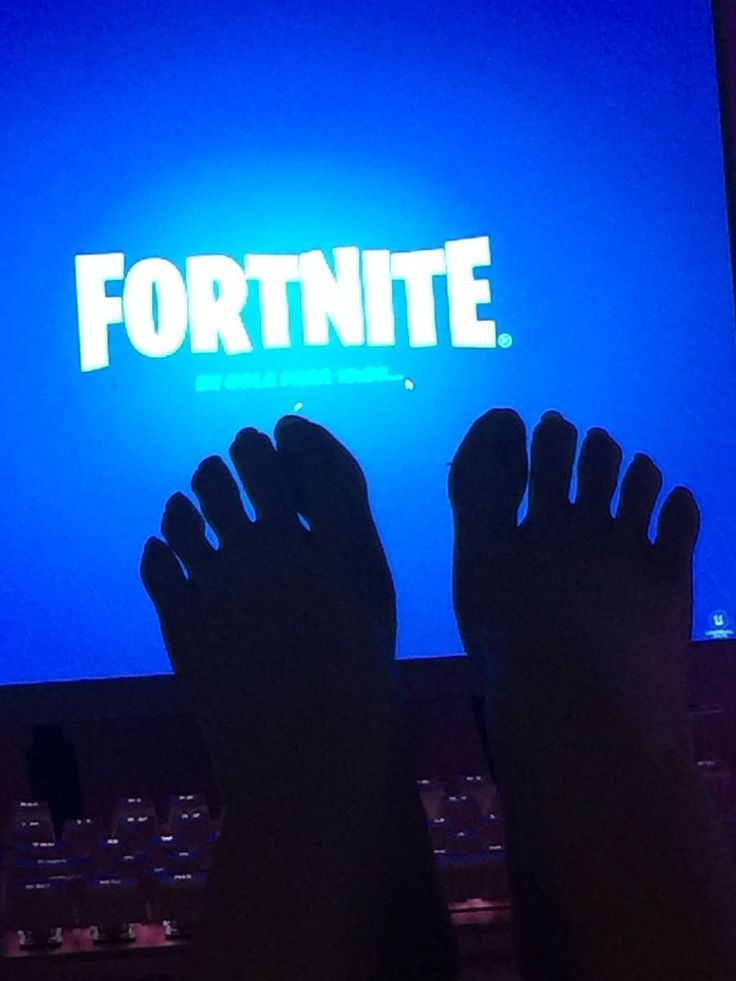 someone's feet are shown in front of a computer screen with the word fortnite on it