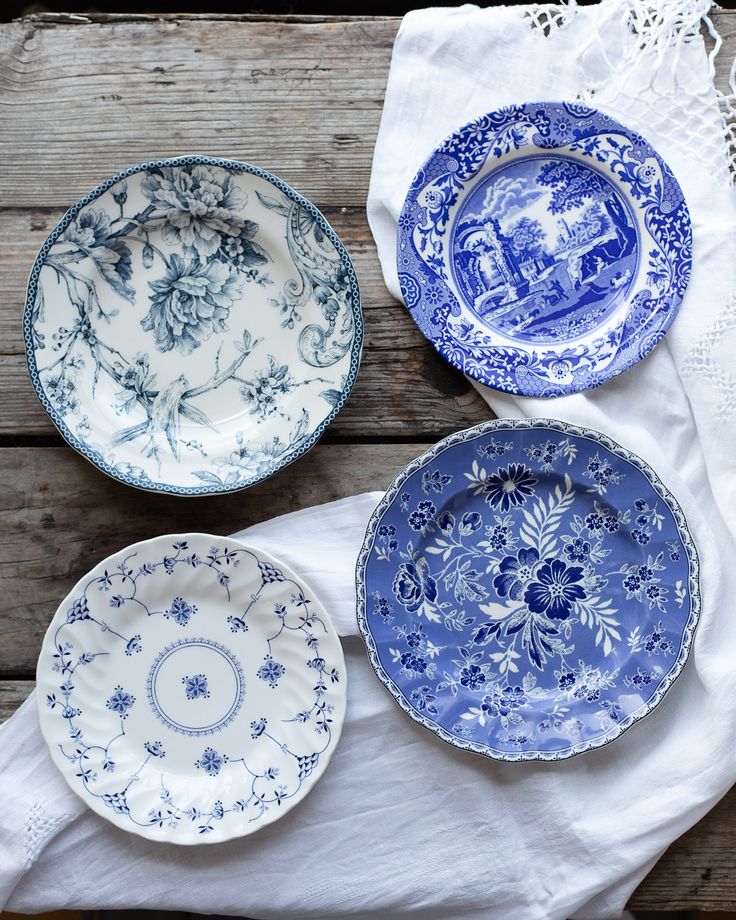 three blue and white plates sitting on top of a wooden table