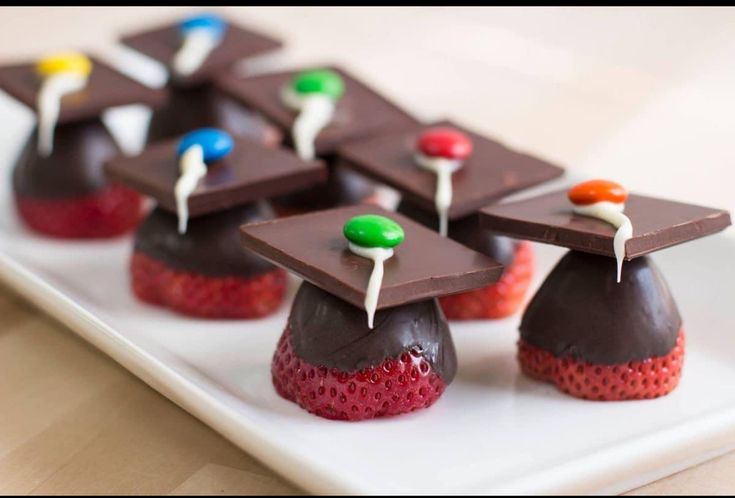 chocolate covered desserts with colorful candies and toppings on a white platter