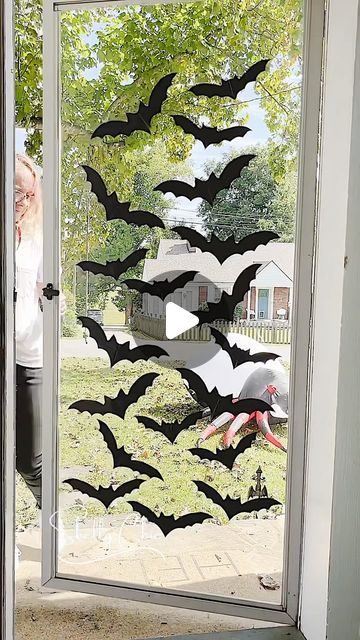 a woman standing in front of a glass door decorated with bats