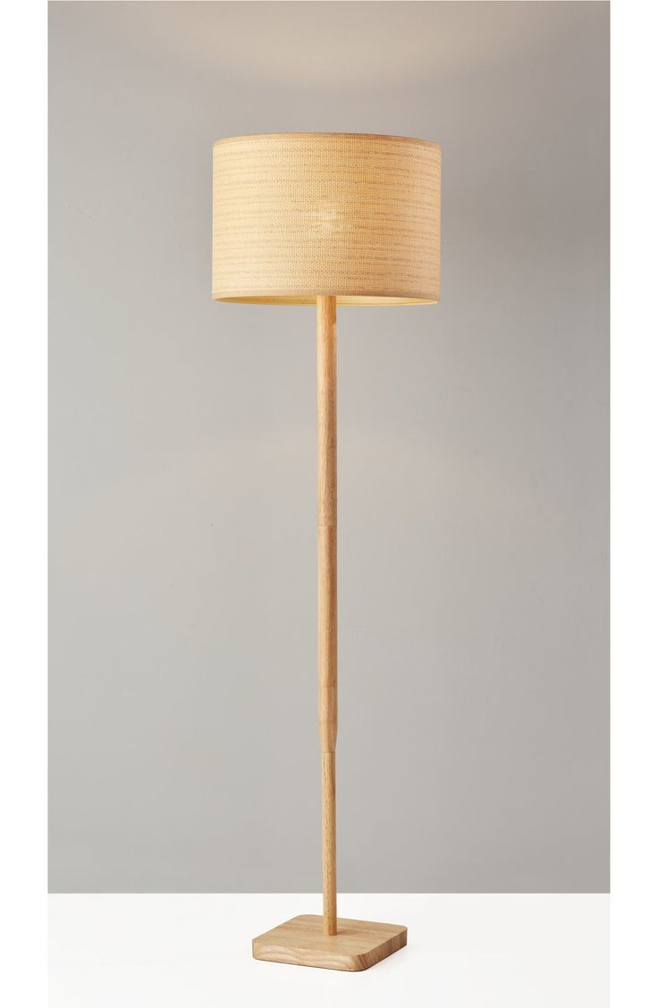 a wooden floor lamp with a beige shade on the base and a white drum light behind it