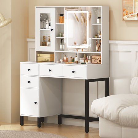 a white desk with drawers and a mirror on it in a living room next to a couch