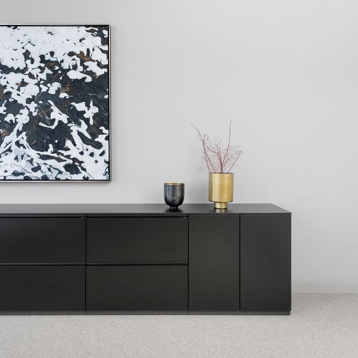 a black cabinet with two vases and a painting on the wall