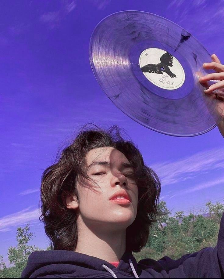 a young man holding up a record in the air with his head tilted to the side