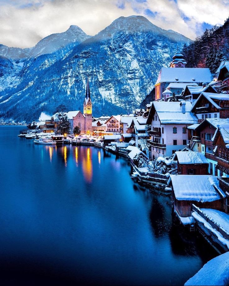 a lake with snow covered mountains in the background and houses on it's sides