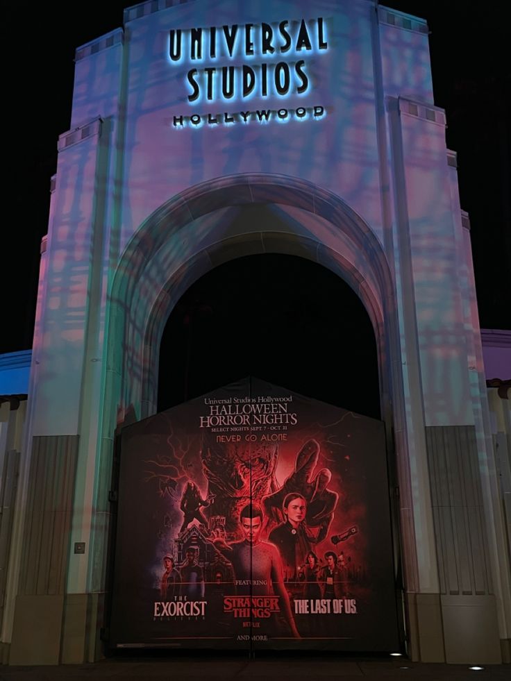 the entrance to universal studios hollywood at night with an advertisement on it's side