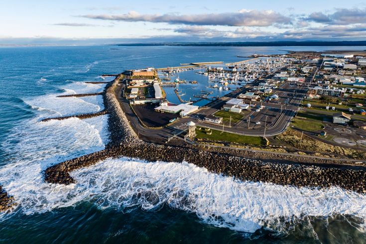 an aerial view of a city by the ocean with waves crashing in front of it