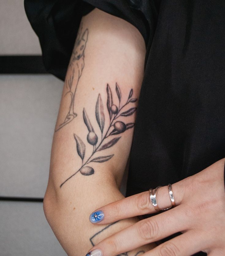 a woman's arm with tattoos on it and a flower tattoo on the wrist