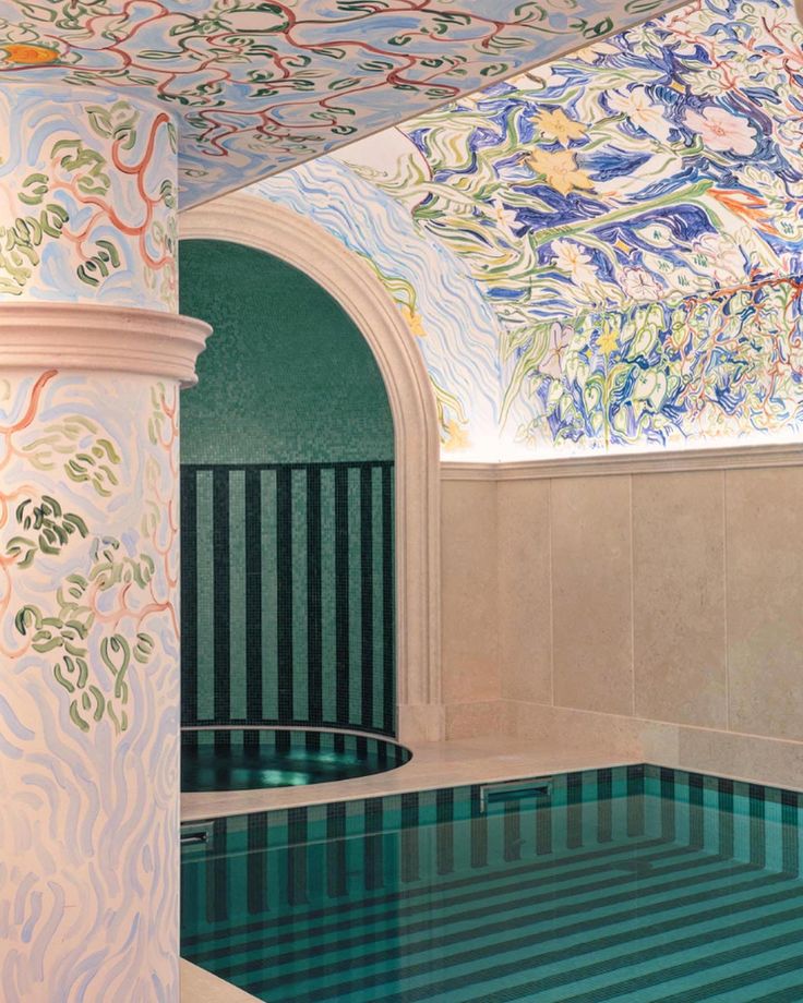 a large indoor swimming pool with an artistic design on the wall and ceiling above it