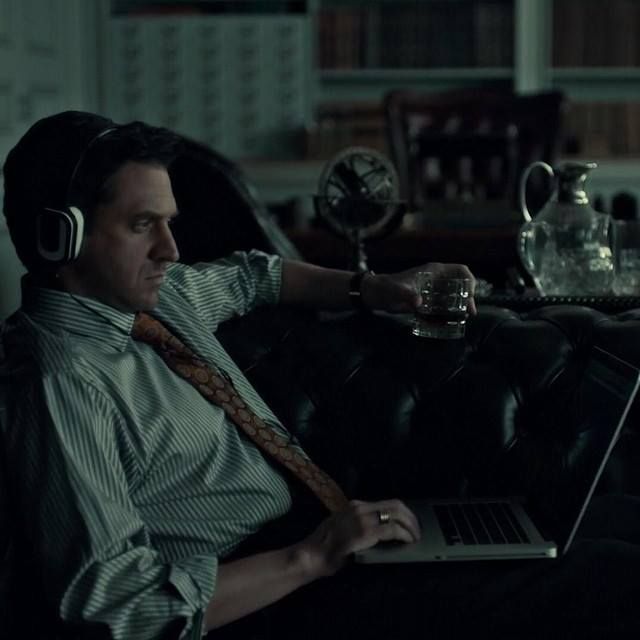 a man sitting on a couch wearing headphones and using a laptop computer in front of him