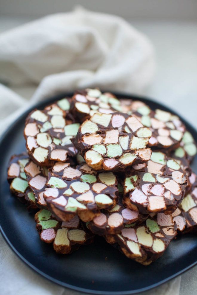 chocolate and marshmallow barkies on a black plate with white cloth in the background