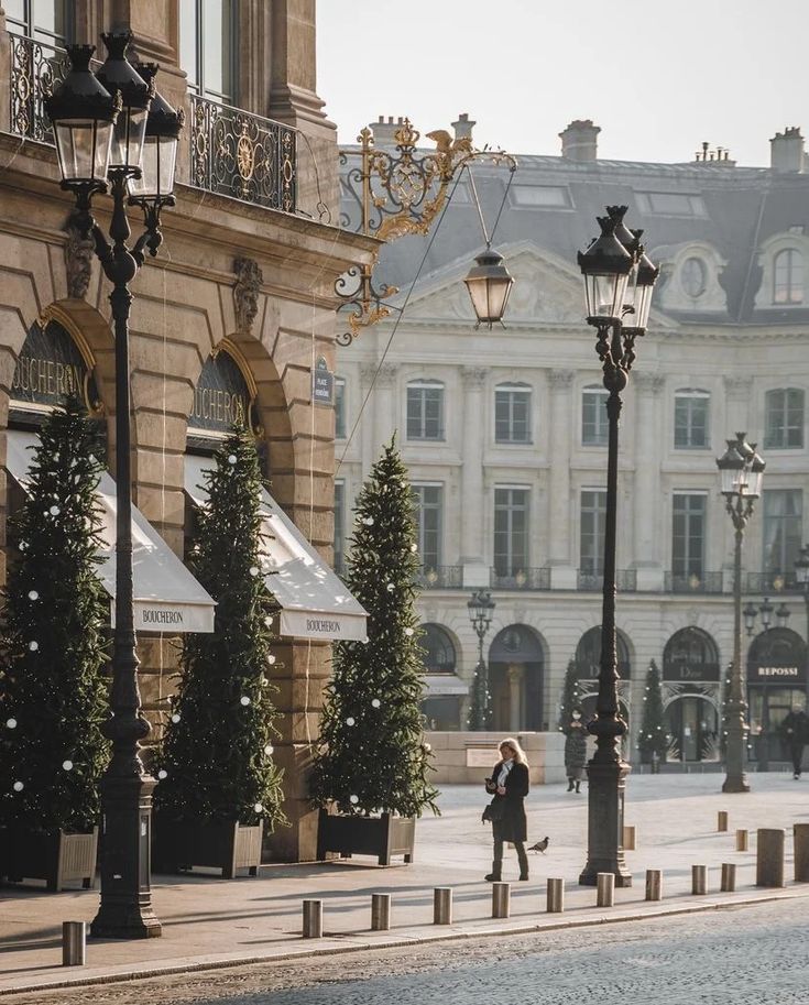 a woman walking down the street in front of a building with lots of lights on it