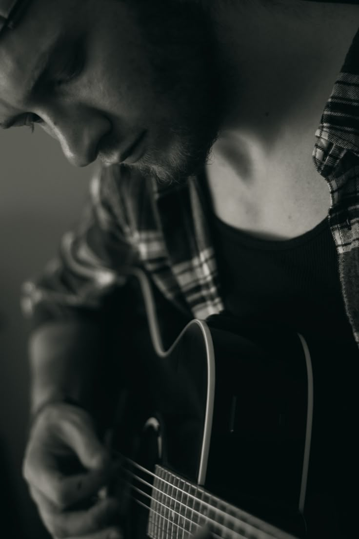 a man is playing an acoustic guitar in black and white