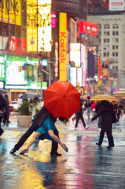 two people kissing under an umbrella in the middle of a busy city street at night