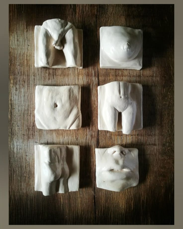 four small white sculptures sitting on top of a wooden table