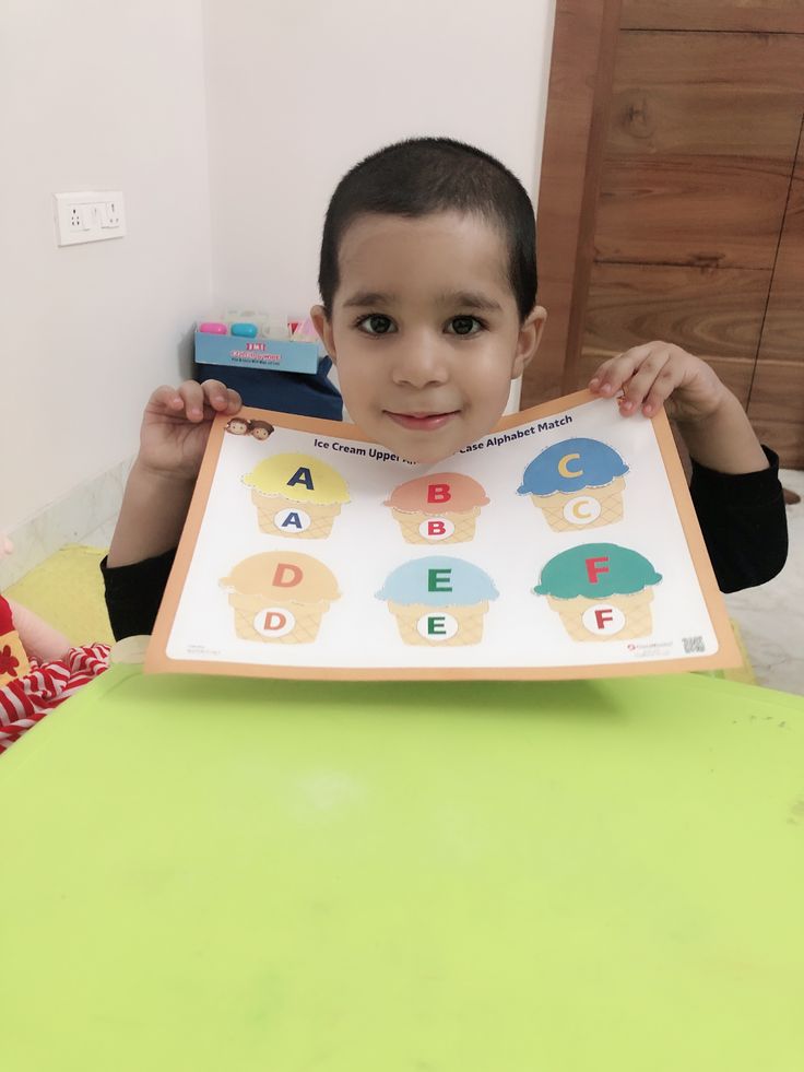 a young boy holding up a poster with letters on it