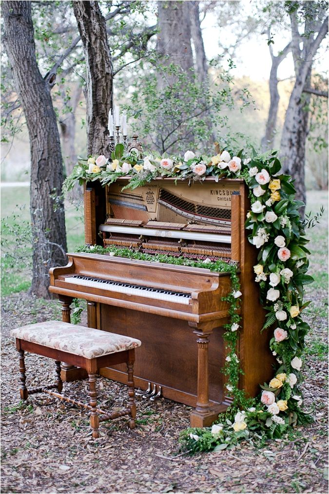 an old piano is adorned with flowers and greenery