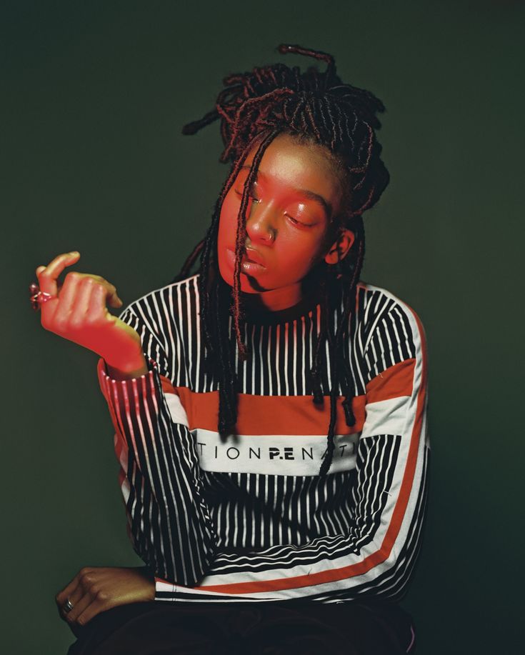 a woman with dreadlocks sitting down and eating a donut in front of her face