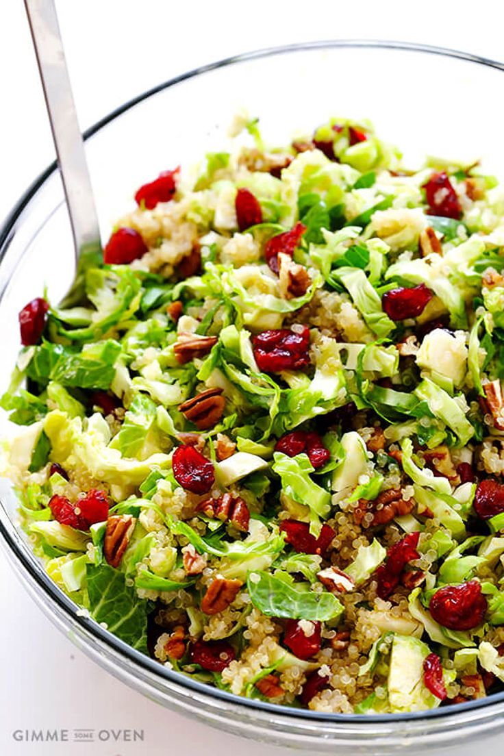 a bowl filled with lettuce, cranberries and nuts