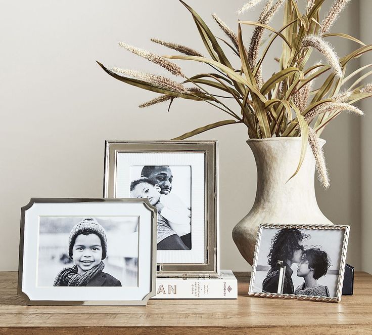 a vase filled with grass next to two pictures and a couple's name on it