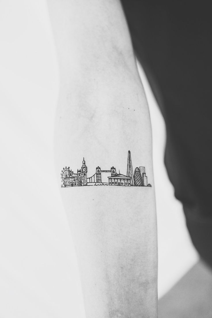 a black and white photo of a cityscape tattoo on the left upper arm