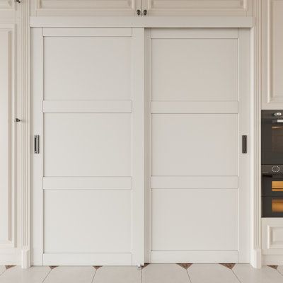 two white doors are open in a room with tile flooring and cabinets on either side