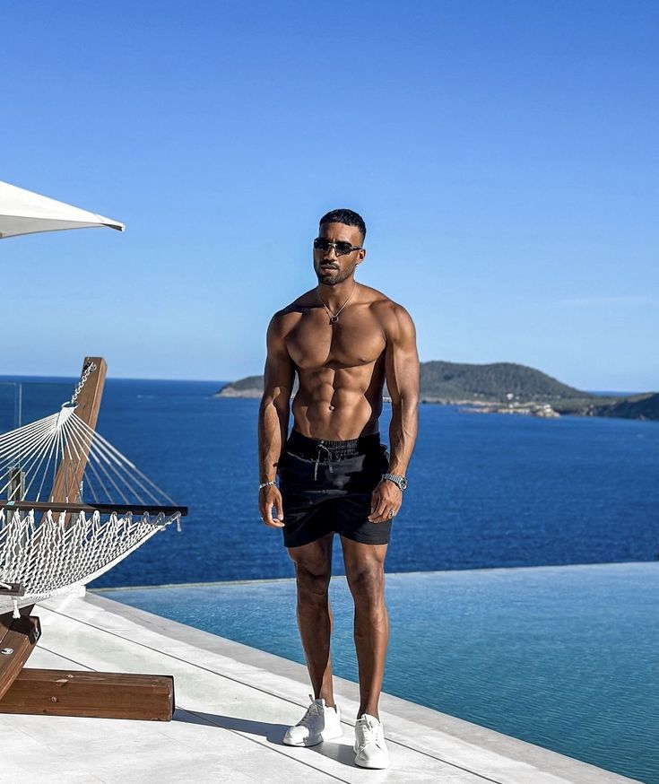 a shirtless man standing next to a hammock