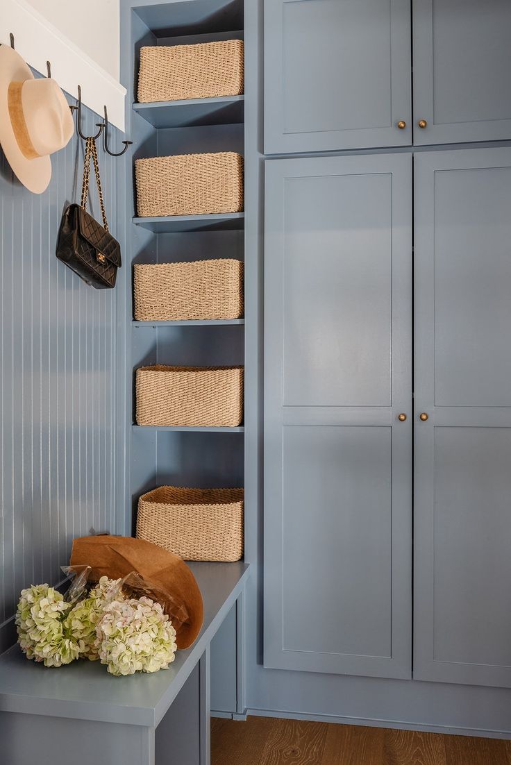 a blue closet with baskets and hats hanging on the wall next to it's shelves