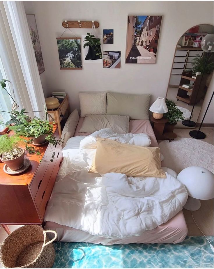 an unmade bed sitting in the middle of a living room next to a window