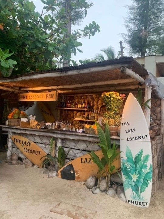 a surfboard sitting in front of a small bar on the side of a beach